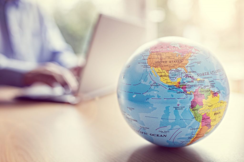 Close-up of a globe with a laptop user in the background, representing Mocean SMS Messaging Campaign solutions empowering Philippine businesses worldwide.